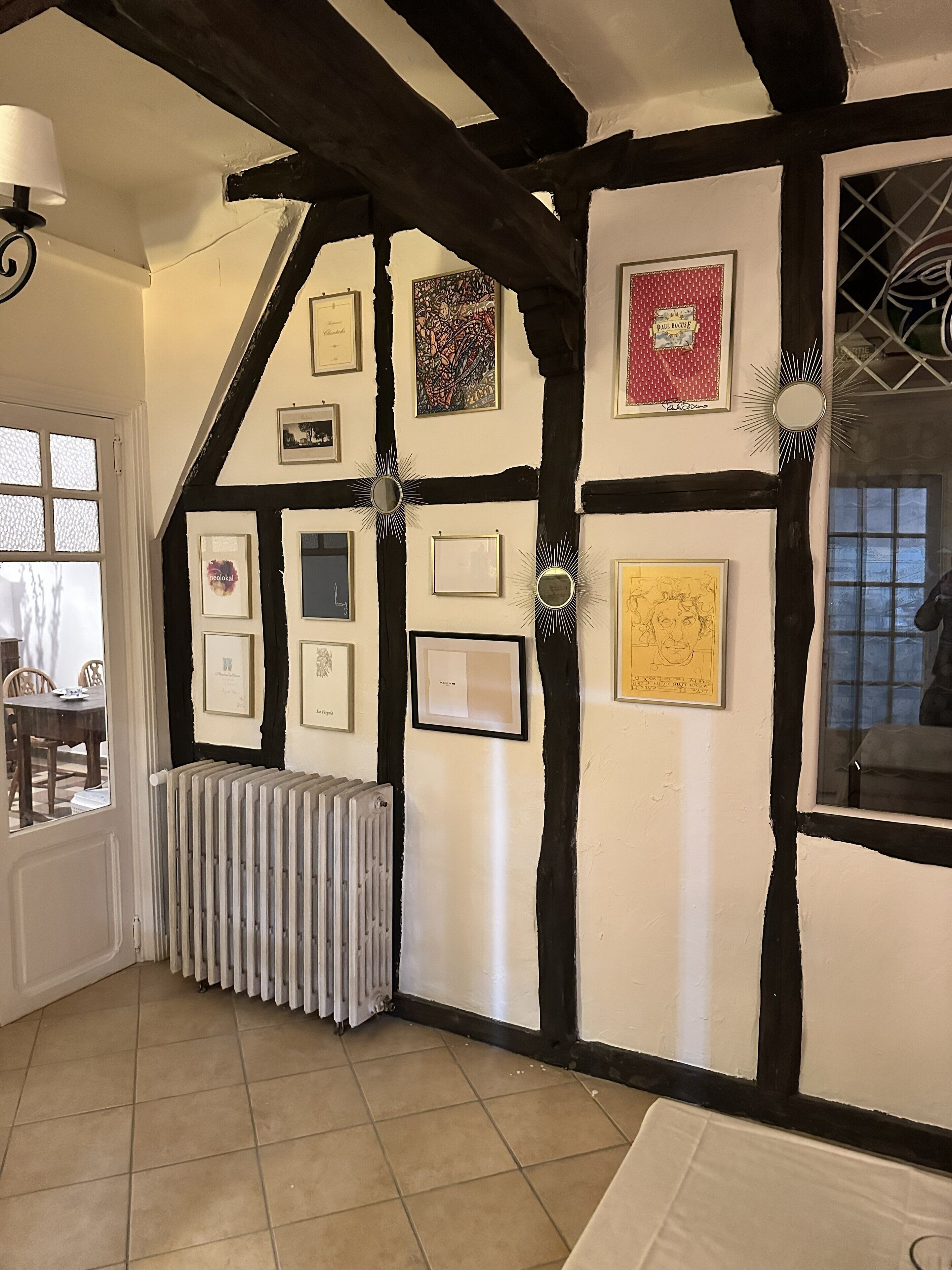 A room with exposed wooden beams, a radiator, and framed artwork on the walls.