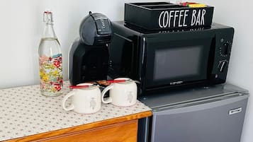 Una cuineta amb cafetera, microones, nevera i un armari.