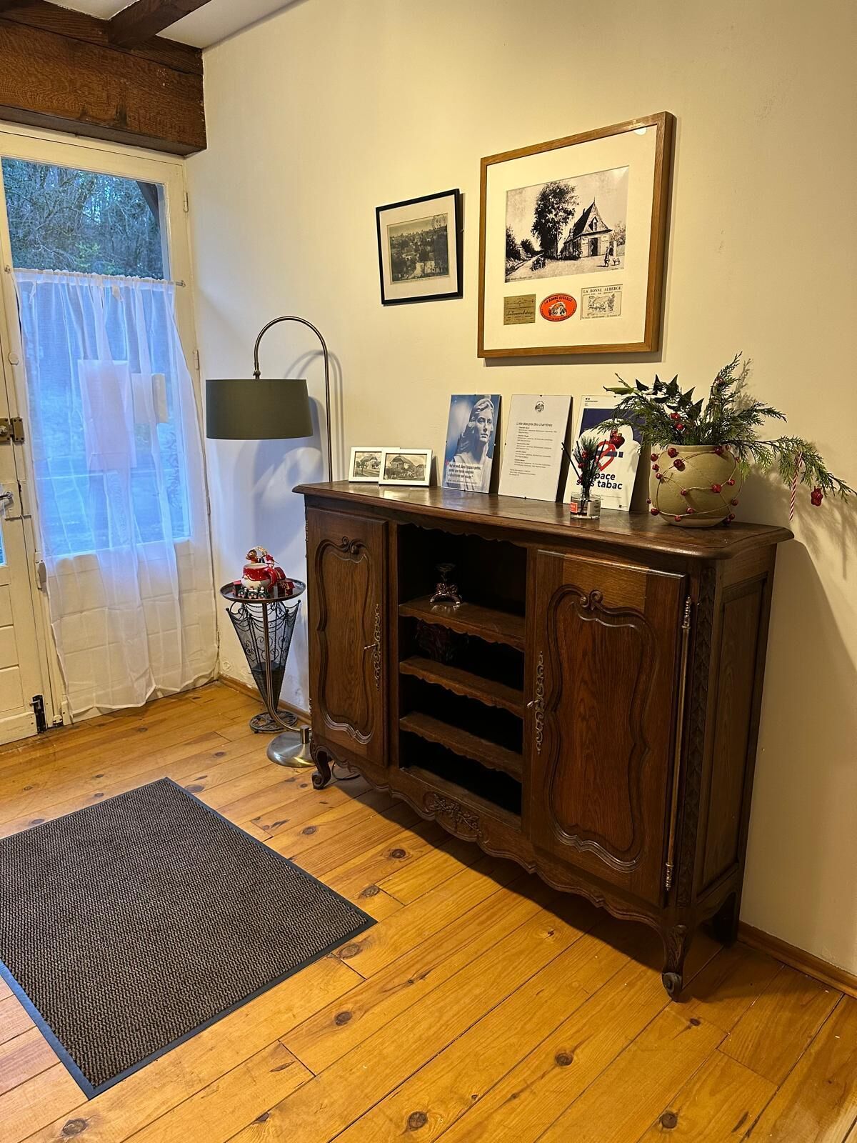 Una habitación con un armario de madera, un cuadro enmarcado, una mesita con una lámpara y un felpudo en el suelo.