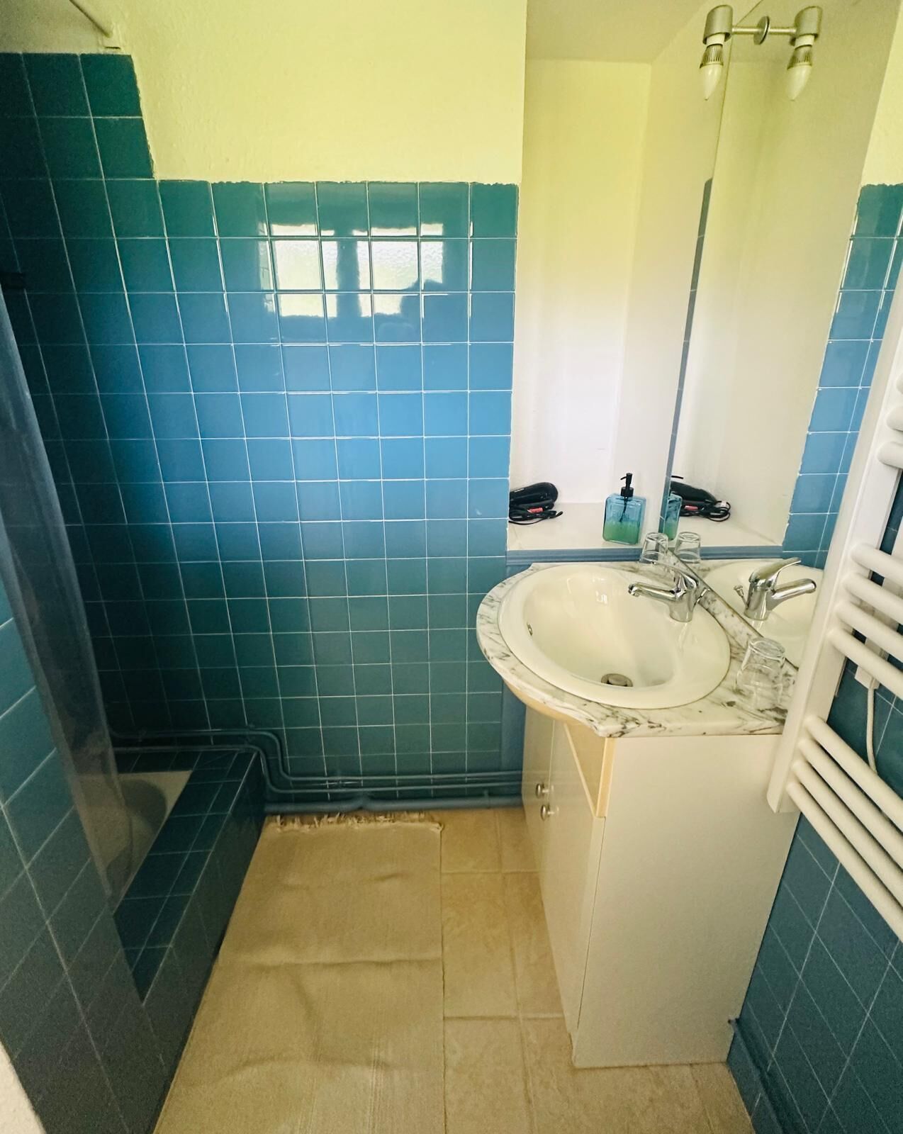 Een badkamer met blauwe tegels, een wastafel, een spiegel en een handdoekrek.