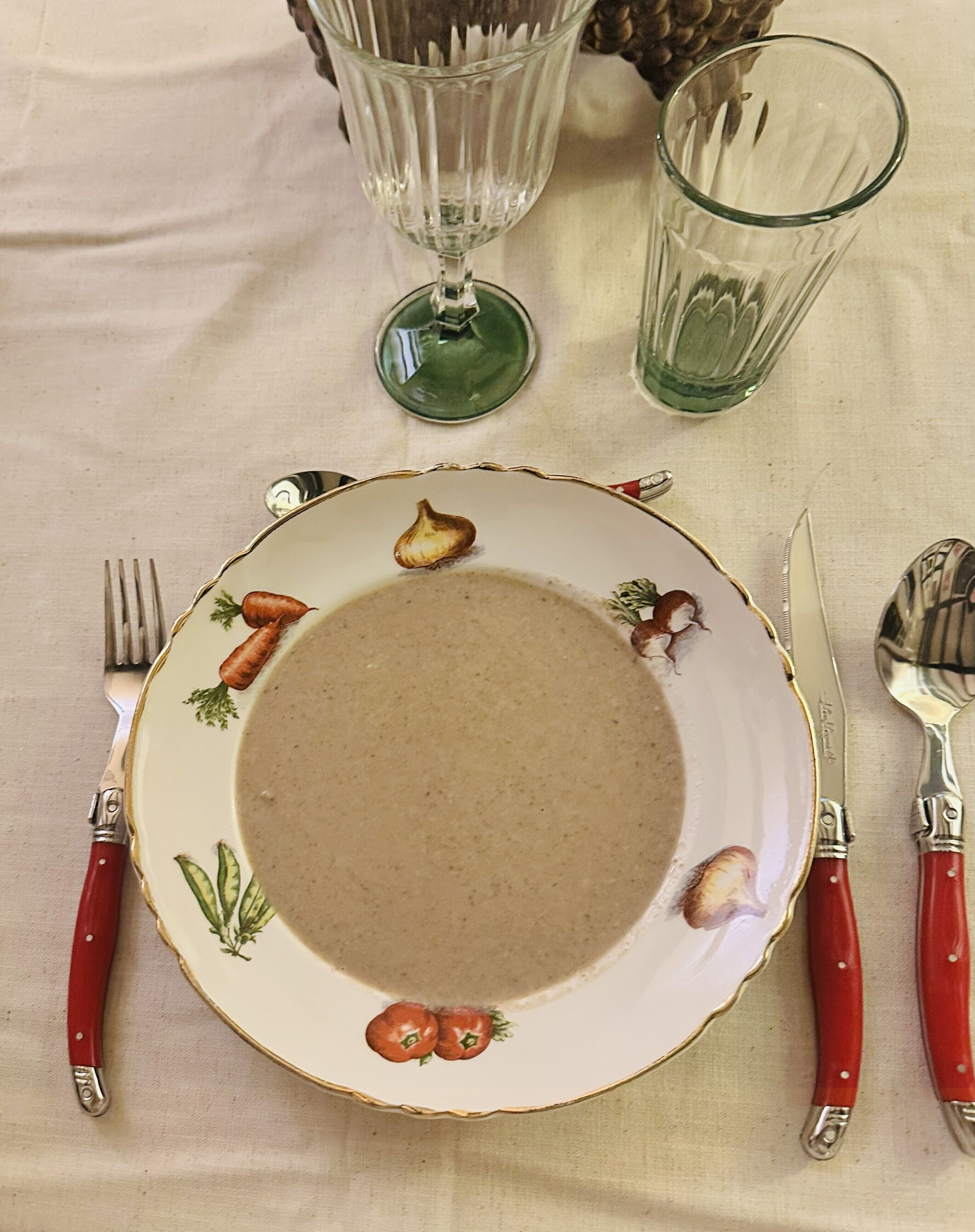 Una mesa de comedor dispuesta con un plato, cubiertos y cristalería.