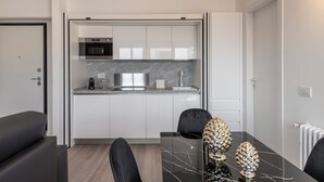 Eine moderne Küche mit weißen Schränken, einer Marmorarbeitsplatte und einem eingebauten Ofen.