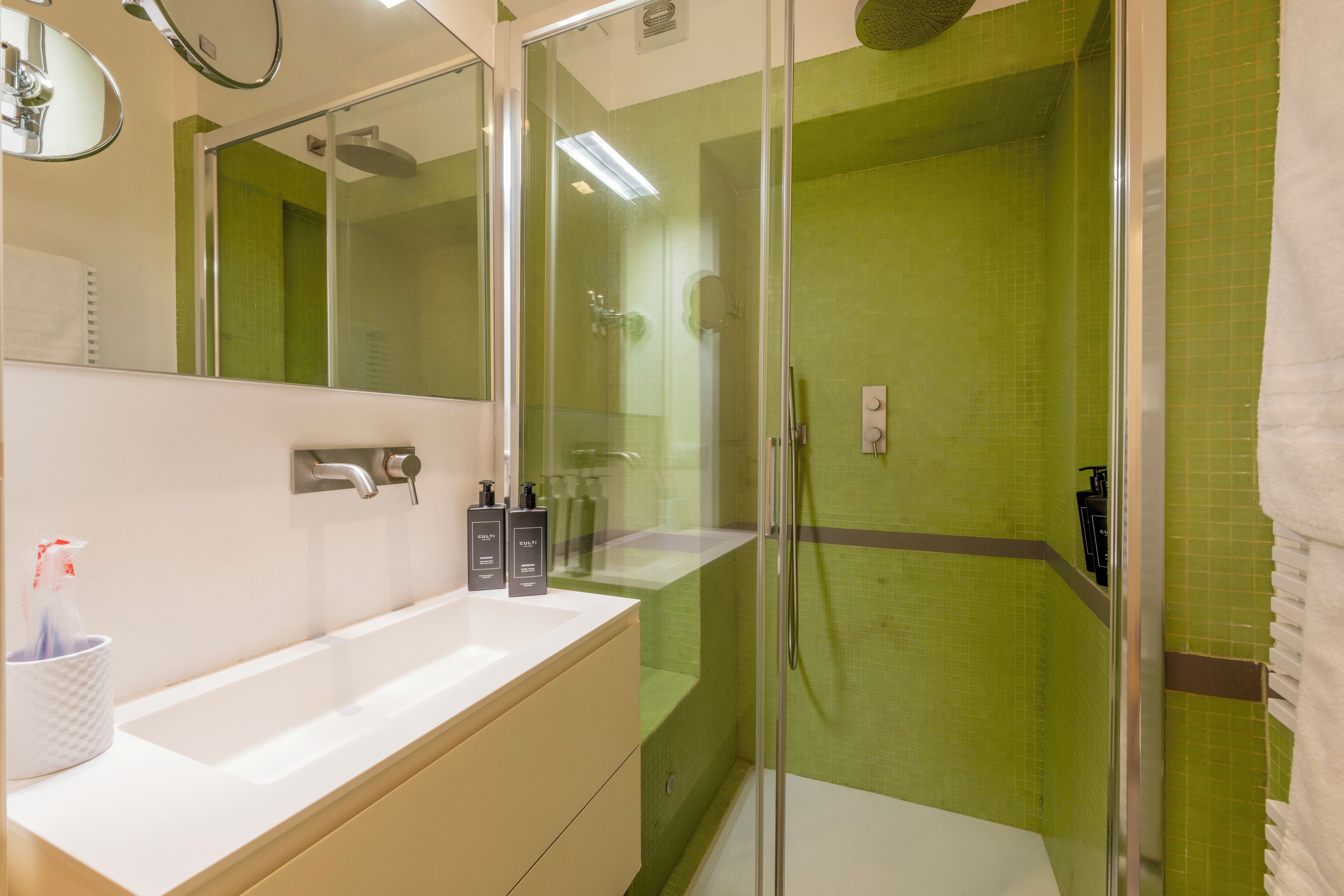 A modern bathroom with a glass-enclosed shower, a white sink, and a mirror above it.