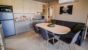 Kompakti keittiö, jossa on ruokailutila, musta nahkasohva ja seinälle asennettu ilmastointilaite.