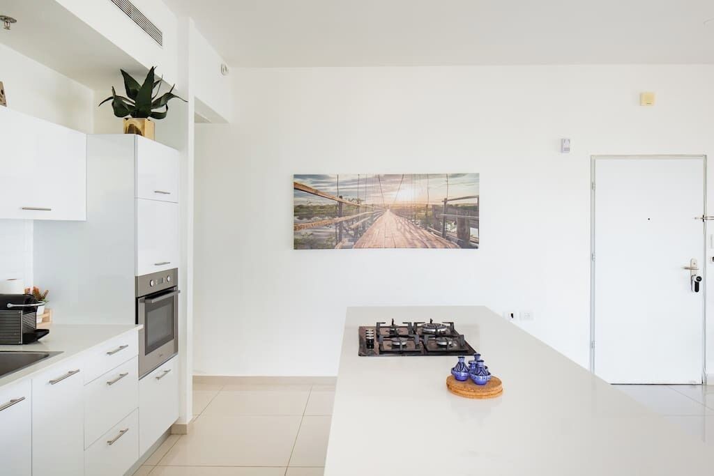 Une cuisine moderne avec des meubles blancs, une cuisinière et un coin repas équipé d’une table.