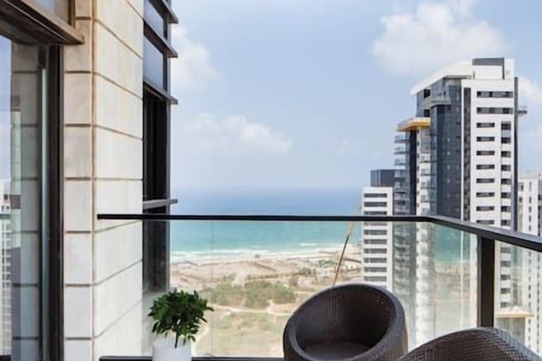 Balcony seating area invites quiet moments overlooking the sea and surrounding city skyline.