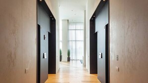 A modern hallway with wooden flooring, dark walls, and a large window at the end. - Luxury Apt Tower | Sea View Bat Yam | Mamad (Bat Yam)