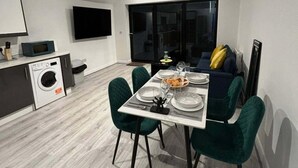 A modern dining area with a table set for four, green chairs, and a sofa with yellow cushions. - Seaside Cottage Escape in Southport (Southport)