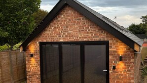 A brick house with a large sliding glass door and a sloped roof. - Seaside Cottage Escape in Southport (Southport)