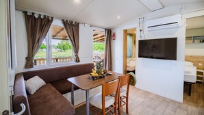 Een knus woongedeelte met een bank, eettafel en televisie.