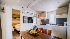 Una cocina compacta con comedor, microondas, estufa y refrigerador pequeño.