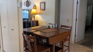 Un comedor con una mesa y sillas de madera, una lámpara y un televisor.