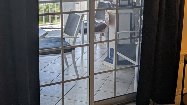 Ein Zimmer mit einer Schiebeglastür, die zu einem Außenbereich mit Terrasse und Sitzgelegenheit führt.