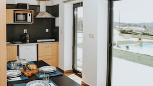 Een moderne keuken met een eethoek, uitzicht op een zwembad, en een deur naar een buitenruimte.