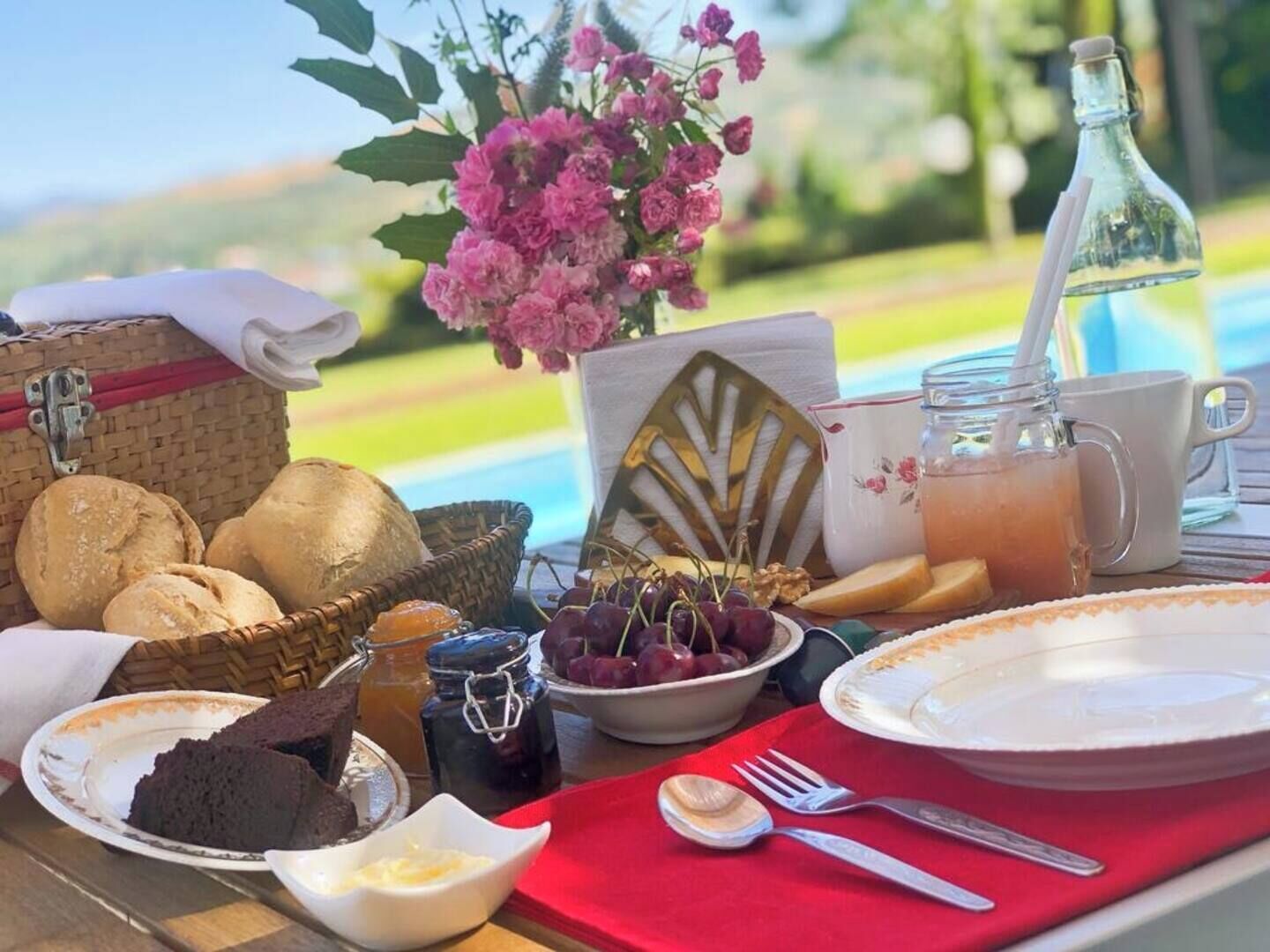 Ein Frühstücksbuffet mit Brot, Gebäck, Früchten und Getränken am Pool.