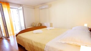 A hotel room with a large bed, a window with curtains, a radiator, and a wooden floor.