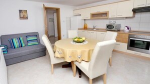 A modern kitchen with white cabinets, a microwave, an oven, and a dining area with a table and chairs.