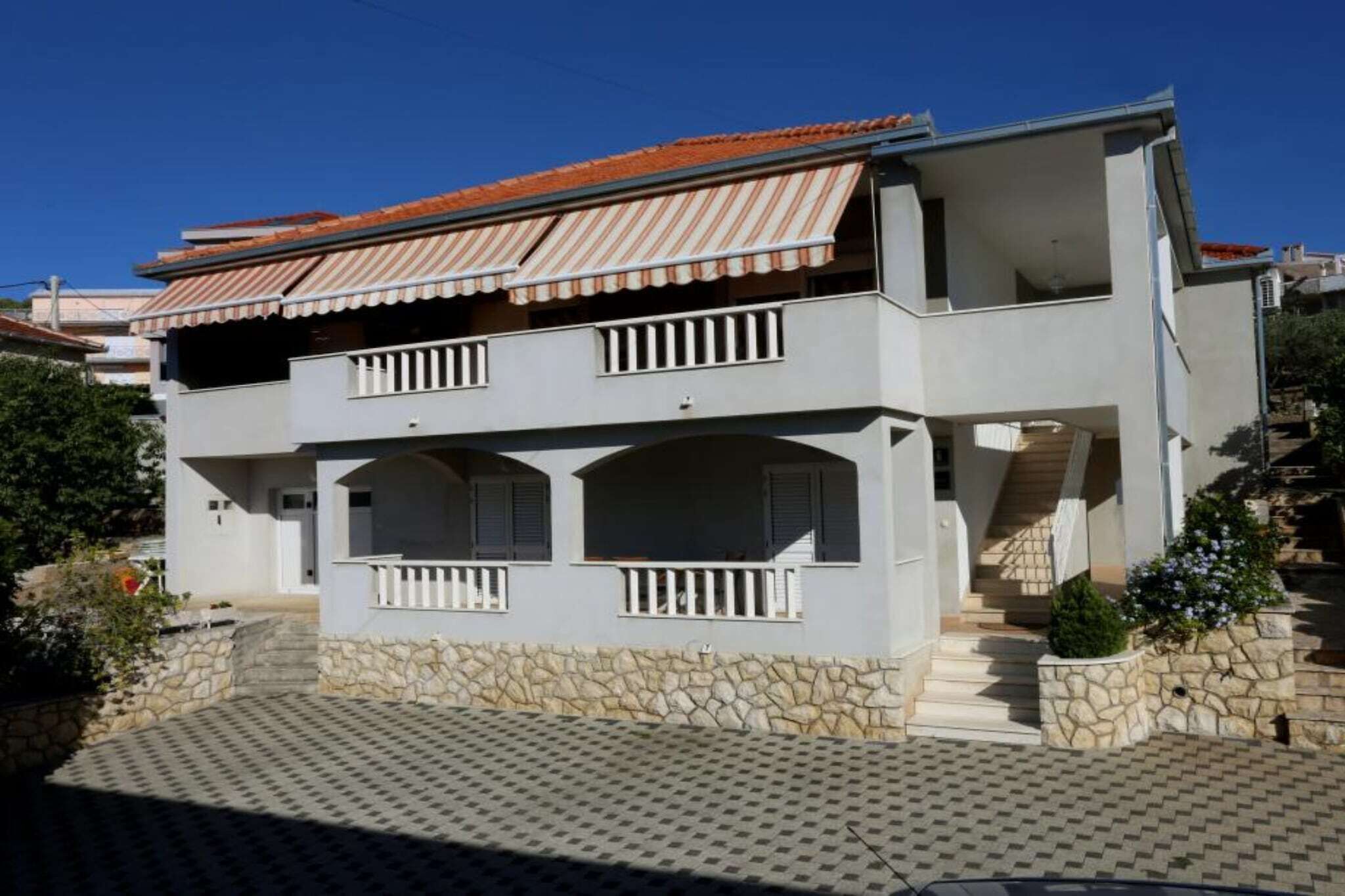 Une maison à deux étages avec une façade en pierre, un balcon et un toit recouvert de tuiles.