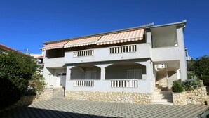 A two-story building with a stone facade, a tiled roof, and a balcony with railings. - One-Bedroom Apartment With Terrace (A2) (Trogir)