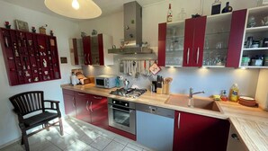 Una cocina moderna con armarios rojos, encimera de madera, horno empotrado y lavavajillas.