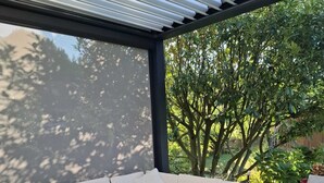 Un espacio de estar al aire libre cubierto con un sofá modular y un reposapiés de mimbre.