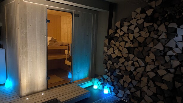 Una sala de sauna con paredes de madera, un banco y una pila de leña.