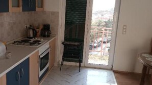 A kitchen with a gas stove, oven, and a coffee maker. There is a sliding glass door leading to a balcony. - Spacious & Cozy Apartments Dugi Rat (Dugi Rat)