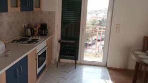 A compact kitchen with a gas stove, oven, and a small dining table. - Spacious & Cozy Apartments Dugi Rat (Dugi Rat)