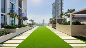 Una terrazza panoramica con erba sintetica, edifici moderni e palme.