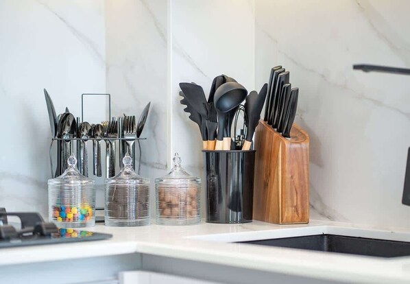 A kitchen counter with utensils, a knife block, and glass containers.