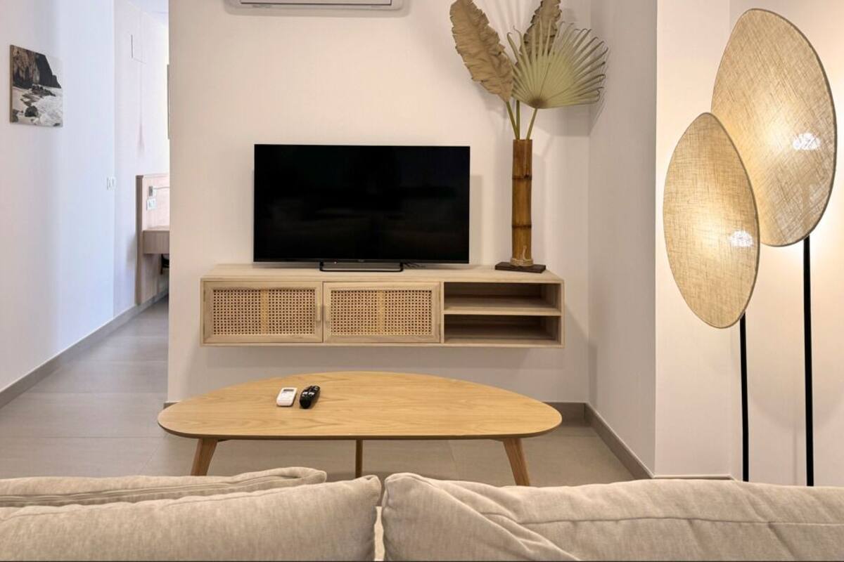 A modern living room with a flat-screen TV on a wooden console, a round coffee table, and a sofa.