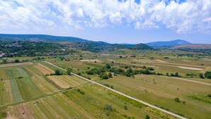 An aerial view of a rural landscape with fields, a road, and distant hills.