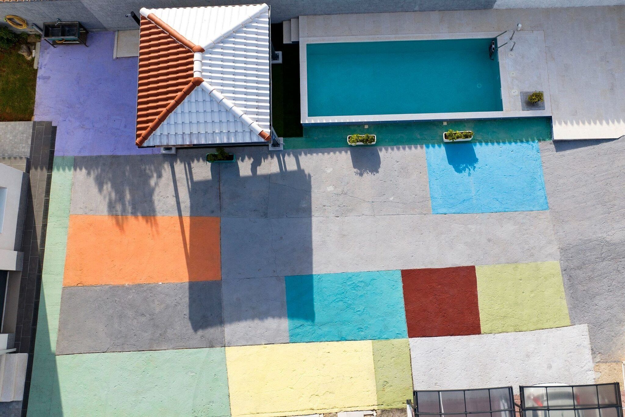 Eine Dachterrasse mit Pool, Ziegeldach und farbig gestalteter Bepflanzung.