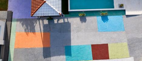 Eine Dachterrasse mit Pool, Ziegeldach und farbig gestalteter Bepflanzung.