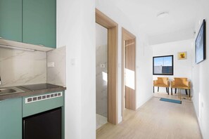 A modern kitchen with a built-in stove, a dining area with two chairs, and a view of the sky through a window.