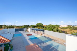 A rooftop terrace with a pool, solar panels, and a view of the surrounding landscape.