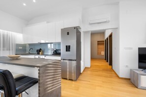 A modern kitchen with a stainless steel refrigerator, a built-in oven, and a coffee machine.