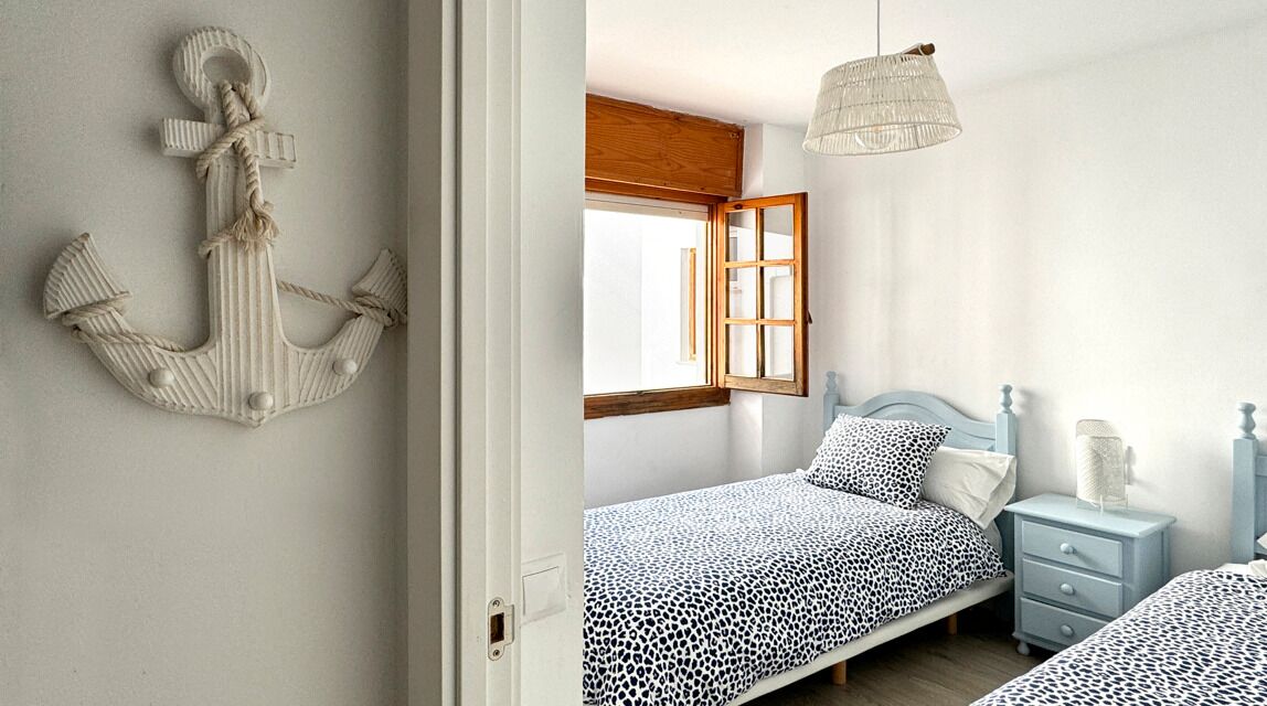 Un dormitorio con cama, mesita de noche y lámpara colgante.