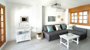 Un salon moderne avec un canapé gris, une table d’appoint blanche et un meuble blanc.