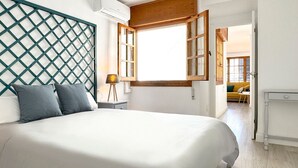 Une chambre à coucher avec un lit, une tête de lit en bois, une fenêtre et une table de chevet avec une lampe.