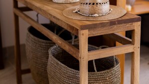 Une table en bois, avec des paniers en osier et un chapeau de paille.