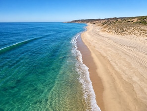 Een strand met helderblauw water en een zandstrand.