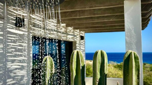 Une douche moderne dotée de plusieurs jets d’eau, d’une porte en verre et offrant une vue sur l’océan.