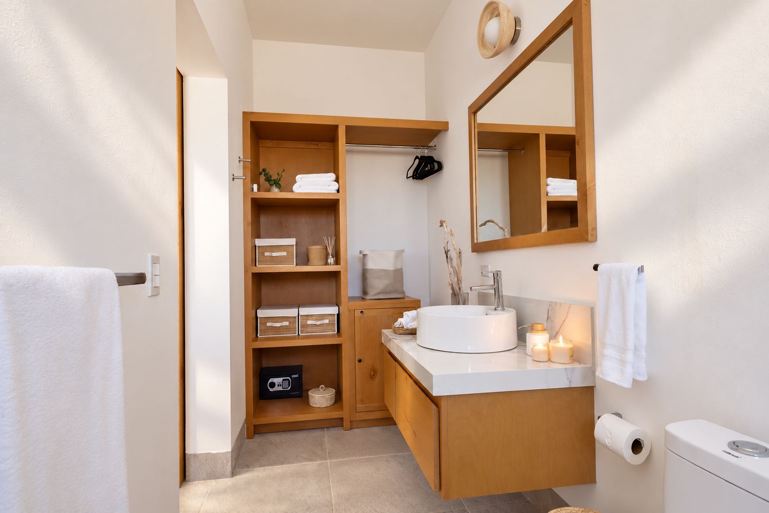 Un baño moderno con tocador de madera, un lavabo redondo y un espejo grande.