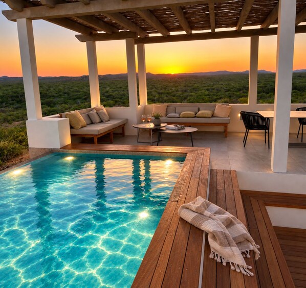 A pool area with a wooden deck, a sofa set, and a table with chairs.