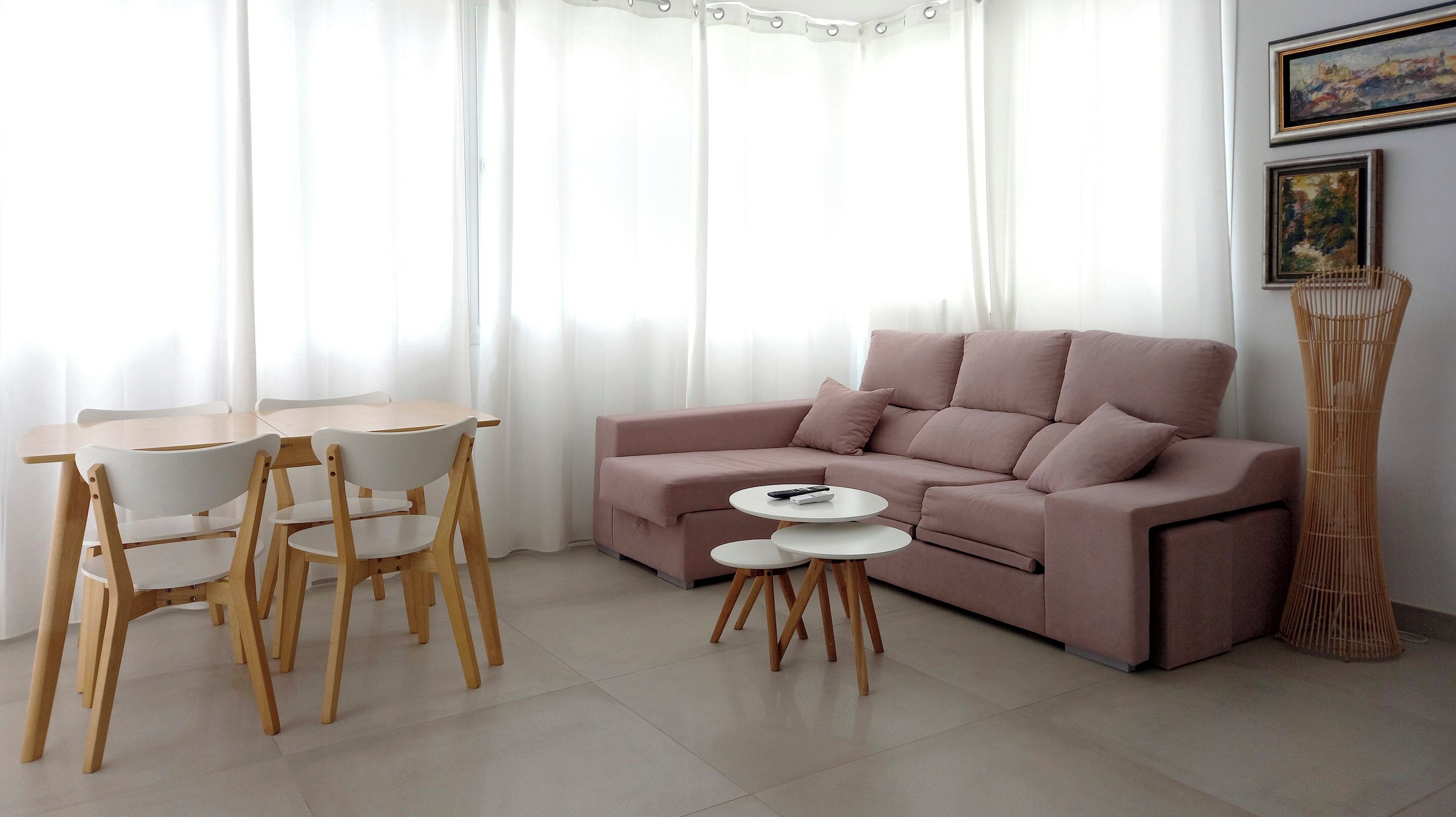 Una sala de estar con sofá, dos sillones, una mesita y una planta decorativa alta.