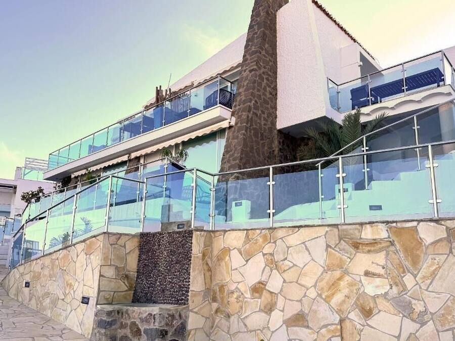 Un edificio moderno de varios pisos con balcones de vidrio y fachada de piedra.
