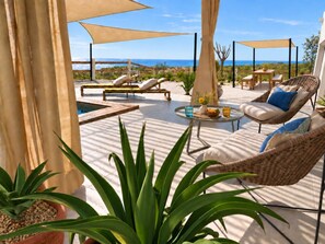 An outdoor patio with lounge chairs, a round table, and potted plants.