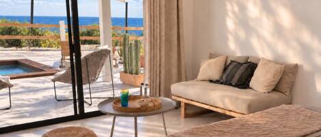 A modern living room with a sofa, a round table, and a view of the ocean.