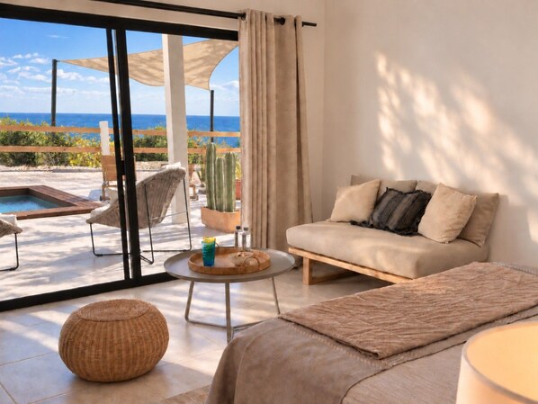 A modern living room with a sofa, a round table, and a view of the ocean.